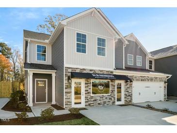 Two-story home with gray and beige siding, stone accents, and a two-car garage at 712 Apple Churn Dr, Fuquay Varina, NC 27526