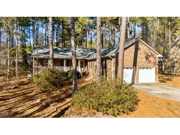 Brick house with two-car garage and porch, nestled among tall pines at 3064 Carolina Way, Sanford, NC 27332