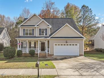 Two story house with beige siding, white garage door, and a front porch at 7821 Lagenaria Dr, Angier, NC 27501