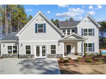 Two story home with gray siding, stone accents, and double doors at 9516 Woodriver Dr, Zebulon, NC 27597