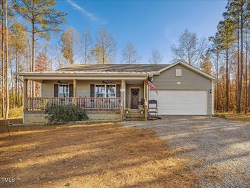 Gray house with a white garage door, front porch, and American flag at 505 Lucian Hilliard Rd, Goldston, NC 27252