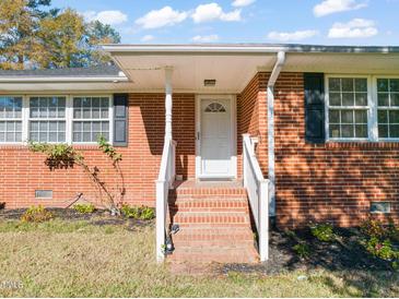 Brick ranch house with covered porch and a landscaped yard at 5813 Cheek Rd, Durham, NC 27704