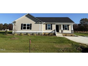 Newly built home with a beige exterior, landscaped lawn, and a paved driveway at 29 Pate Landing Dr, Selma, NC 27576