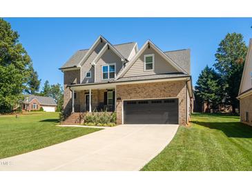 Two-story house with brick and siding, a large driveway, and landscaping at 407 Eagle Ct, Henderson, NC 27536