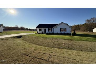 White house with black roof, landscaping, and a grassy yard at 186 Pate Landing Dr, Selma, NC 27576