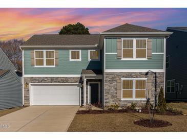 Two-story house with stone and siding, two-car garage, and landscaped yard at 62 Tanglewood Pl, Angier, NC 27501