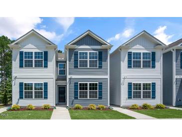 Three-unit townhome building with white and gray siding, landscaping, and walkways at 8656 Brixton Shay Dr, Raleigh, NC 27616