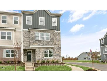 Three-story townhome with stone and siding exterior, steps leading to the entrance, and landscaping at 2243 Horton Park Drive, Apex, NC 27539