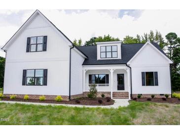 Two-story farmhouse with white siding, black windows, and a covered porch at 75 Kettle Creek Dr, Zebulon, NC 27597