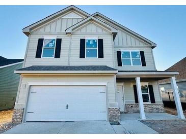 Two-story home with light beige siding, brick accents, and a two-car garage at 83 Meath Ct # 209, Clayton, NC 27520