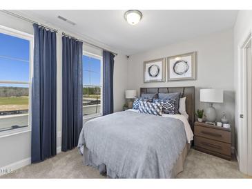 Bright bedroom with large windows, plush bedding, and wood nightstand at 510 Village Branch Ln # 45, Wake Forest, NC 27587