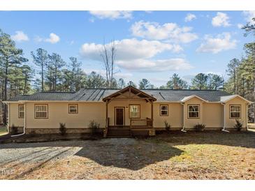 House exterior featuring a light beige color, large windows, and a wooden covered porch at 7815 Dodsons Crossroads, Hillsborough, NC 27278