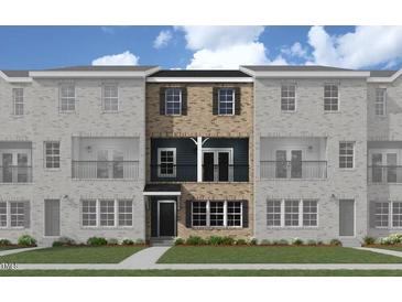 Attractive three-story townhome with brick and siding exterior, front balcony, and green lawn at 217 Broomgrove Way, Wake Forest, NC 27587
