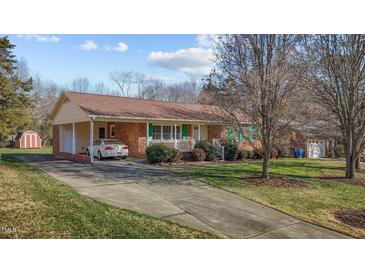 Charming brick ranch home with a covered carport, front porch, and green shutters at 920 Essex Dr, Graham, NC 27253