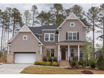 Charming two-story home with a welcoming front porch and a brick and siding exterior at 9520 Wood River Dr, Zebulon, NC 27597