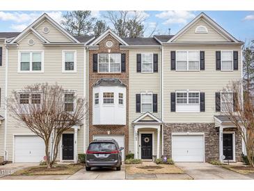 Three-story beige townhouse with stone accents and a two-car garage at 2765 Wyntercrest Ln, Durham, NC 27713