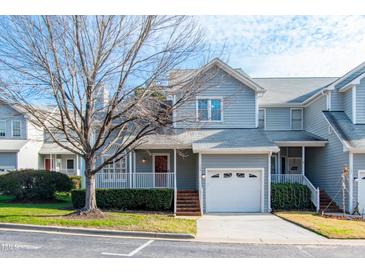 Gray two-story townhome with a white garage door and brick steps at 8300 Hempshire Place # 104, Raleigh, NC 27613