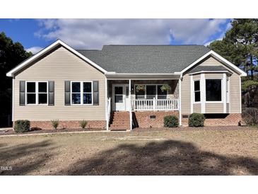 Beige house with gray roof, stone accents, and landscaping at 106 Bradley Dr, Benson, NC 27504