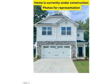 Two-story home with stone and white vinyl siding, two-car garage, and landscaping at 211 Drayton Hall Ln, Sanford, NC 27330