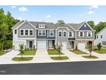 Four townhouses with gray siding, two-car garages, and landscaping at 6336 Lady Eliza Ln, Raleigh, NC 27610