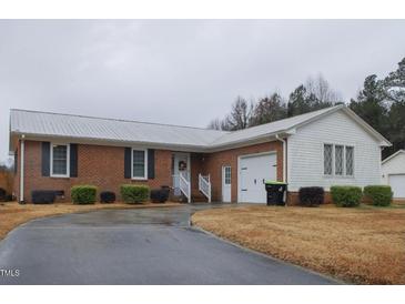 Brick ranch house with attached garage and landscaped yard at 202 S Wilson St, Kenly, NC 27542