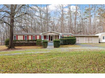 Tan mobile home with red shutters, front porch, and landscaped yard at 1705 Old Nc 10 Hwy, Hillsborough, NC 27278