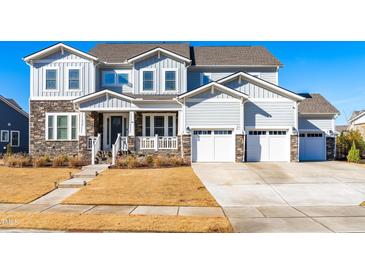 Two-story house with gray siding, stone accents, and a two-car garage at 212 Chickasaw Plum Dr, Holly Springs, NC 27540