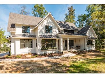 Modern farmhouse exterior with white siding, a metal roof, and a wraparound porch at 34 Chestnut Creek Way, Chapel Hill, NC 27516