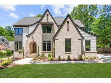 Two-story home with brick and siding, showcasing a charming front porch and landscaping at 7621 Wingfoot Dr, Raleigh, NC 27615