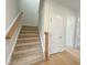 Carpeted staircase with wood railing and access to upper level at 73 Sage Ln # 008, Four Oaks, NC 27524