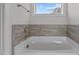Relaxing corner bathtub with gray tile surround and window at 345 Sutherland Dr, Franklinton, NC 27525