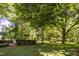 Landscaped backyard with mature trees and a pergola at 6720 Mebane Oaks Rd, Mebane, NC 27302