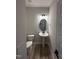 Modern bathroom with pedestal sink, round mirror, and gray flooring at 1031 Westerland Way # 46, Durham, NC 27703