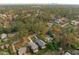 Aerial view of a house nestled in a tree-lined neighborhood with city skyline in the distance at 1435 Duplin Rd, Raleigh, NC 27607