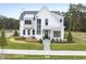 A white two-story home with a black front door, large windows, and landscaping at 3401 Makers Cir, Raleigh, NC 27612