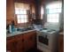 Kitchen featuring wooden cabinets, a white electric stove, and dual windows at 1852 Nc 62 Hwy N, Burlington, NC 27217