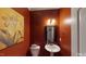 Small powder room with pedestal sink and orange walls at 104 Abbeville Ln, Holly Springs, NC 27540