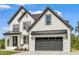 Two-story farmhouse with white siding, dark gray accents, and a three-car garage at 85 Harvest View Way, Franklinton, NC 27525