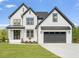Two-story farmhouse with white siding, dark gray accents, and a three-car garage at 85 Harvest View Way, Franklinton, NC 27525