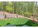 Landscaped backyard with lush lawn and retaining wall, offering a private wooded setting at 1817 N Lakeshore Dr, Chapel Hill, NC 27514