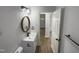 Modern bathroom with white vanity, round mirror, and wood-look flooring at 825 Chalmers St, Durham, NC 27707