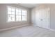 Empty bedroom with neutral-colored carpet and white closet doors at 1713 Grassy Falls Ln, Wendell, NC 27591