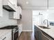 White kitchen with stainless steel appliances, quartz countertops, and an open view to the adjacent rooms at 1713 Grassy Falls Ln, Wendell, NC 27591