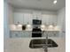 Modern kitchen with white cabinets, quartz countertops, and stainless steel appliances at 231 Village Walk Dr, Clayton, NC 27527