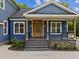 House exterior featuring a charming blue facade, a wooden front door, and a stone-accented porch at 5121 Watkinsdale Ave, Raleigh, NC 27613