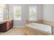 Spa-like bathroom featuring a corner soaking tub and large windows at 11603 Broadfield Ct, Raleigh, NC 27617