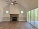 Spacious living room featuring a stone fireplace, built-in shelving, hardwood floors, and sliding glass doors leading to a patio at 200 Whistlers Cv, Louisburg, NC 27549