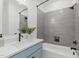 Modern bathroom with a blue vanity, gray tile shower, and bathtub at 614 Rocky Knob Ct, Raleigh, NC 27601