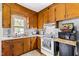 Bright kitchen with wood cabinets, white appliances, and a window overlooking the backyard at 8401 Mitchell Mill Rd, Zebulon, NC 27597