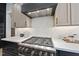 Close-up of gas cooktop with stainless steel range hood and marble backsplash at 7417 Dover Hills Dr, Wake Forest, NC 27587